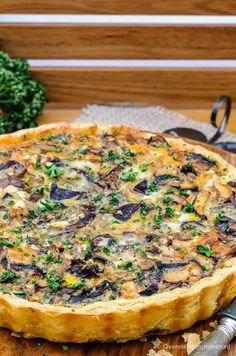 a quiche with mushrooms and parsley on a cutting board