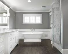 a large white bathtub sitting next to a walk in shower under a bathroom window