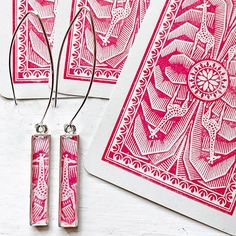 two pairs of earrings with pink and white designs on them, sitting next to each other