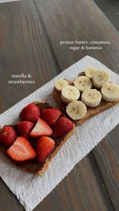 two slices of bread with sliced bananas and strawberries on top, sitting on a napkin