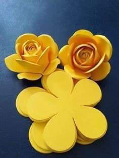 three yellow paper flowers sitting on top of a blue table next to eachother