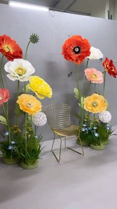 an arrangement of flowers in vases sitting on a table next to a wire chair