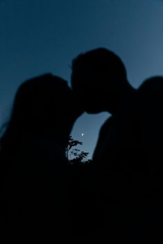 the silhouette of two people kissing at night