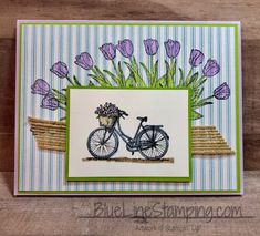 a handmade card with a bicycle and flowers on the front, sitting on a wooden surface