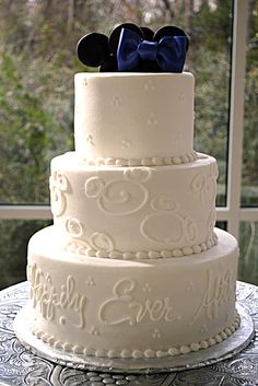 a three tiered wedding cake with mickey ears on top