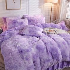 a bed covered in purple fluffy blankets and pillows