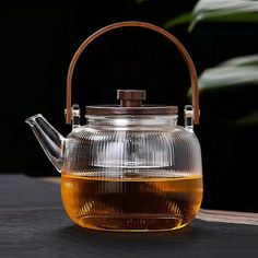 a glass tea pot with a wooden handle