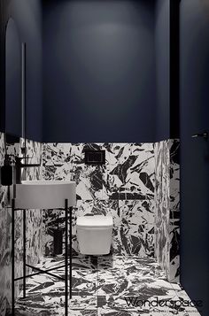 a black and white tiled bathroom with a toilet, sink and mirror in the corner