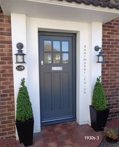 a blue front door with two black planters