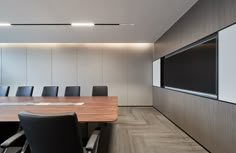 an empty conference room with black leather chairs and a large screen mounted on the wall