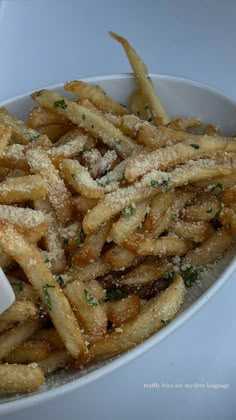 french fries with parmesan cheese and seasoning in a white bowl