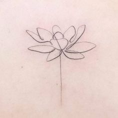 the back of a woman's neck with a single flower tattoo on her left side