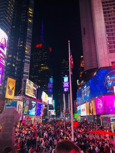 a crowded city street at night with lots of neon signs and buildings in the background