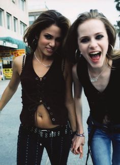 two young women standing next to each other in front of a building with their mouths open