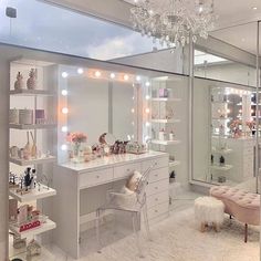 a room with a vanity, mirror and lights on it's walls in front of a large window