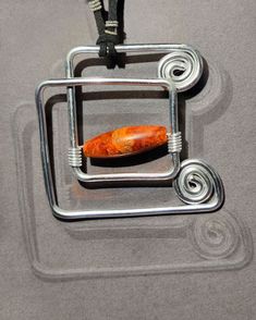 a piece of orange stone sitting on top of a metal object with a black cord