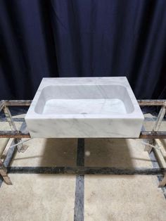 a white sink sitting on top of a tile floor next to a blue curtain and some metal bars