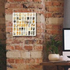 a computer monitor sitting on top of a wooden desk next to a brick wall and potted plants