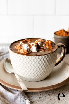 a white bowl filled with hot chocolate and marshmallows on top of a plate