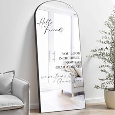 a large mirror sitting on top of a wooden floor next to a chair and potted plant