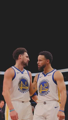 two men standing next to each other in front of a basketball court with the golden state warriors on it