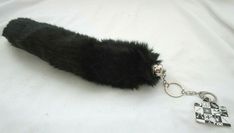 a black furry animal keychain on a white sheet with a checkerboard design