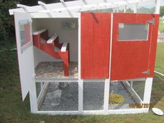 a red and white chicken coop sitting in the grass