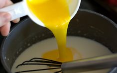 a whisk being poured into a bowl filled with milk and orange juice,