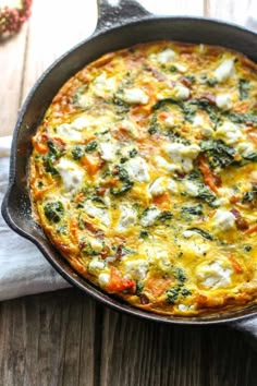 an omelet in a cast iron skillet on a wooden table next to a napkin