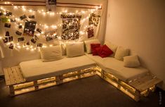 a couch made out of pallets with lights on the wall