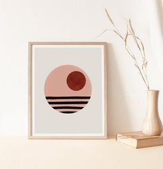 an art print on a shelf next to a vase with dried plant in it and a white wall