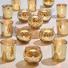 there are many gold colored glass cups and glasses on the table with their lids down