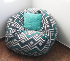 a bean bag chair sitting on top of a tile floor next to a wall with a blue pillow