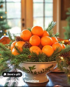 a bowl filled with oranges sitting on top of a wooden table next to pine cones