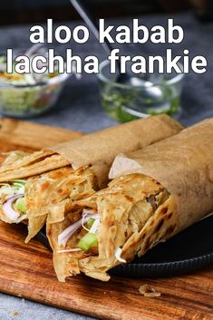 a close up of a burrito on a plate with text overlay that reads aloo kabab lachha frankie