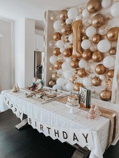 a birthday party with balloons and decorations on the wall behind a table that says happy birthday