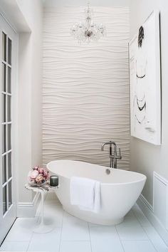 a white bath tub sitting in a bathroom next to a chandelier