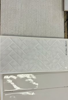 some white tile is laying on the floor in front of a wall with an interesting pattern