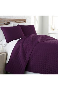 a bed with purple bedspread and pillows