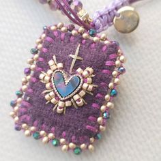 a purple heart with a cross on it is hanging from a cord that's attached to a button