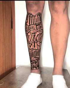 a man's legs with tattoos and words on them, while standing in front of a door