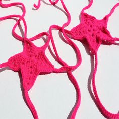 two crocheted pink bikinis are laying next to each other on a white surface