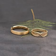 two gold wedding rings sitting next to each other on top of a cloth covered table