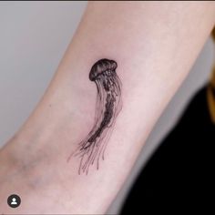 a small black and white jellyfish tattoo on the arm