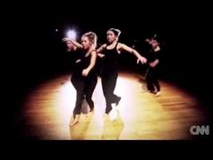 three women are dancing on the floor in black dresses and one is holding her arms out