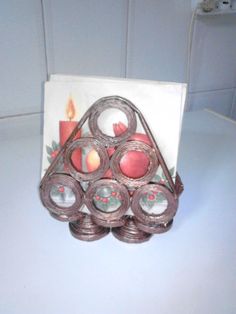 a candle holder made out of coins on top of a white counter next to a card