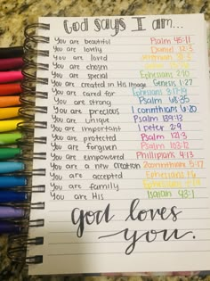 a notebook with the words god loves you written on it and colored crayons next to it