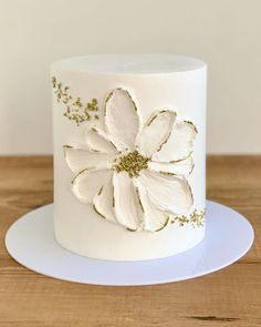 a white and gold decorated cake sitting on top of a wooden table