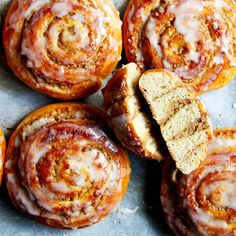 several cinnamon rolls on a baking sheet with one cut in half