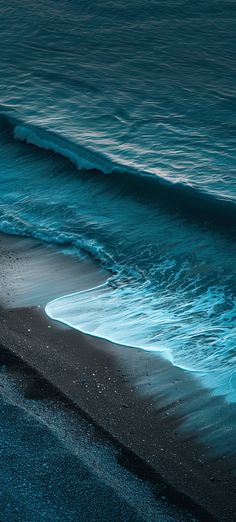 the ocean waves are rolling in and out of the water on the black sand beach